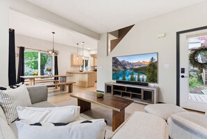 Un salon moderne avec un grand téléviseur à écran plat, une table basse en bois et un canapé.