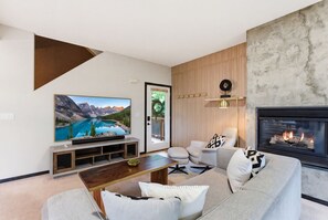 Un salon moderne doté d’un téléviseur à écran plat, d’une cheminée, d’un canapé, d’une table basse et d’un mur décoratif en bois.