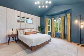 A bedroom with a large bed, a nightstand, a floor lamp, and a window with curtains.