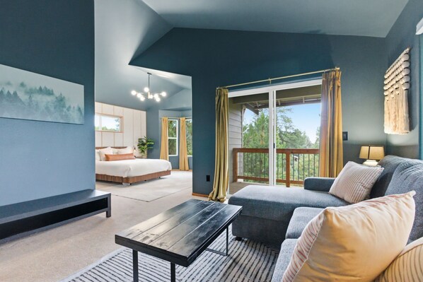 A modern room with a bed, a sofa, a coffee table, and a balcony with curtains.