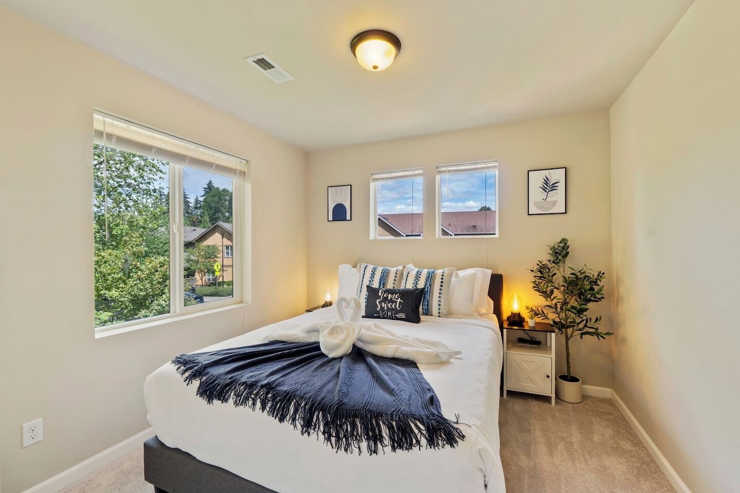 A bedroom with a bed, a window, a bedside table, and a wall-mounted picture.