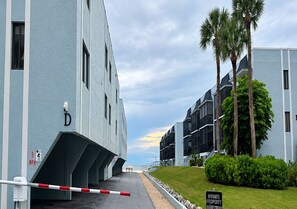 Un ingresso recintato a un edificio con un segnale a forma di 'D', un cartello che indica un limite di velocità di 8 chilometri orari e un cartello che riporta 'PROPRIETÀ PRIVATA'.
