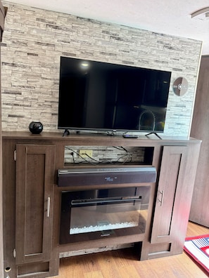 Ein modernes Unterhaltungselement mit Flachbildfernseher, integriertem Backofen und einer Wand mit Steinoptik.