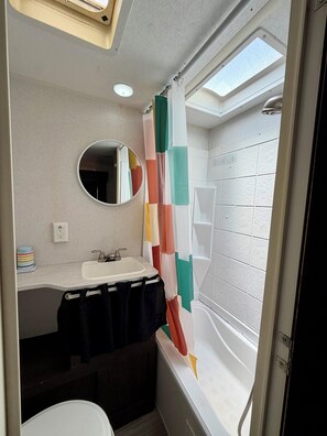 Een badkamer met een witte wastafel, spiegel en douchegordijn met een geometrisch patroon.