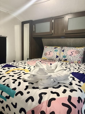 Ein Bett mit einem gemusterten Bettüberwurf und einem weißen Handtuch darauf.