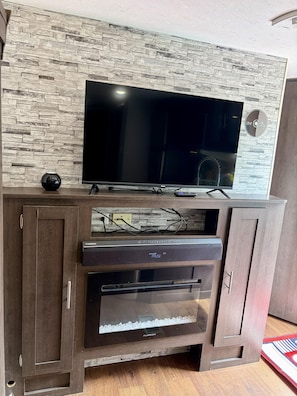 Un mueble moderno de entretenimiento con un televisor de pantalla plana, una consola de videojuegos y un horno integrado.