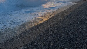 A beach with pebbles, waves, and a boat in the distance. - Cosy apartment in Green Coast Albania-blue flag beach (Palasë)