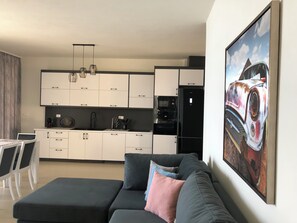 Eine moderne Küche mit weißen Schränken, einem schwarzen Kühlschrank und einem Essbereich mit Tisch und Stühlen.