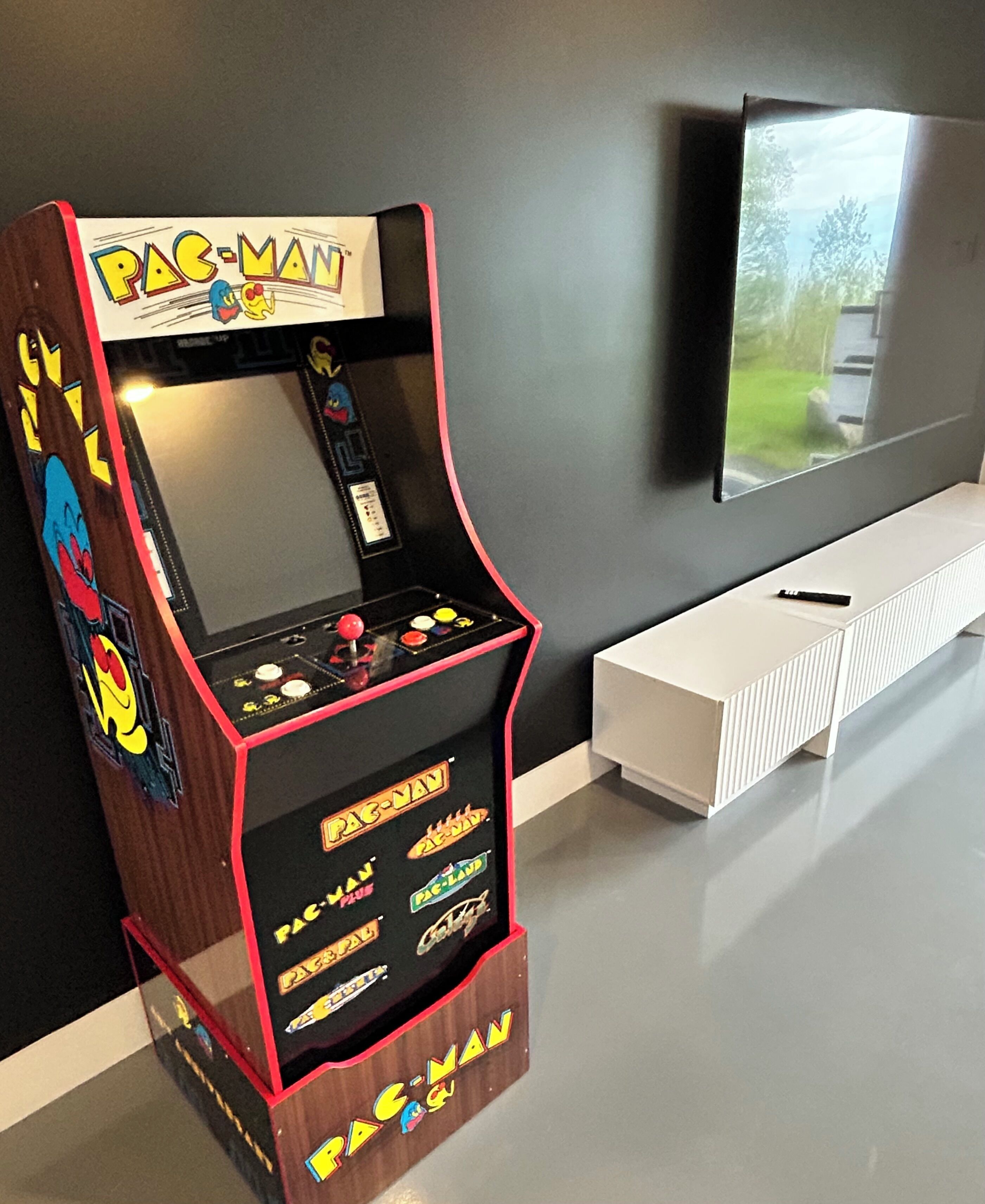 A Pac-Man arcade machine with a monitor displaying a landscape.