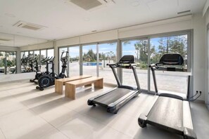 A modern gym with treadmills, stationary bikes, and a bench.