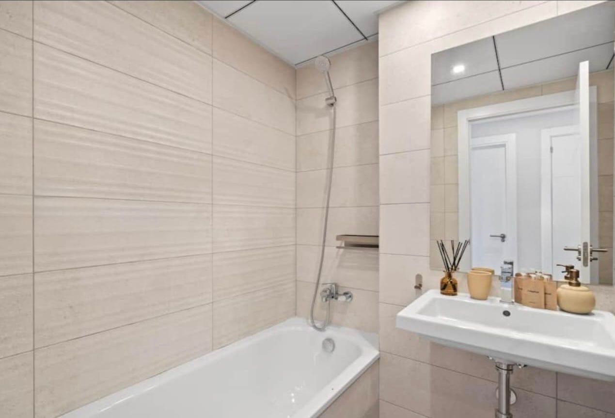 A modern bathroom with a bathtub, a sink, and a mirror.