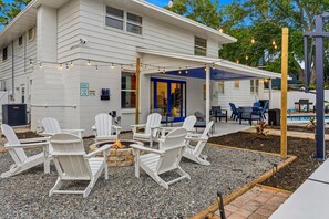 A white building with a covered patio, outdoor seating, and a fire pit. - Neon Tropics - Indoor Mini Golf, Pickleball, Pool (Seminole)