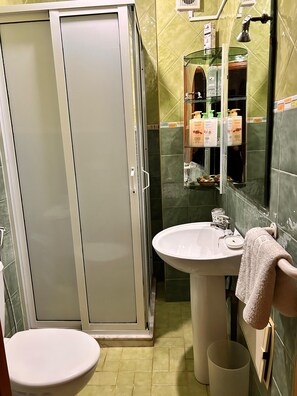 A bathroom with a toilet, a sink, a shower enclosure, and a mirror. - Riad Dar Ania (fès)