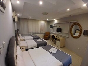 Une chambre d’hôtel avec deux lits, un bureau, une chaise, une télévision, un miroir et une fenêtre avec des rideaux.