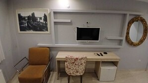 Una habitación con una cama, un escritorio, una silla, un televisor y un espejo.