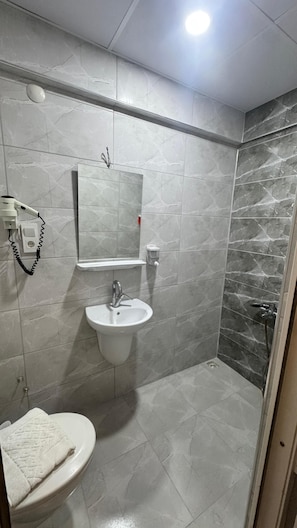 A bathroom with a toilet, sink, mirror, and shower. - PERA CITY OTEL (Samsun)