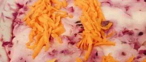 Un plato con vegetales morados y naranjas rallados.