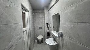 Une petite salle de bain comprenant des toilettes, un lavabo et un miroir.