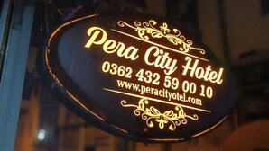 Señalización de neón para el Hotel Pera City con información de contacto y dirección web.