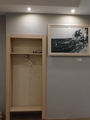 A room with a wooden wardrobe, a framed black and white photograph on the wall, and a ceiling light. - PERA CITY OTEL (Samsun)