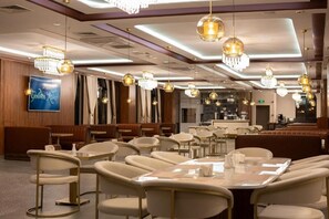 A restaurant with round tables, chairs, chandeliers, and a bar area. - Golden River Hotel by Continent (Arnavutkoy)