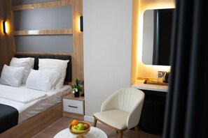 A modern hotel room with a bed, bedside table, chair, and a small table with fruit. - Golden River Hotel by Continent (Arnavutkoy)
