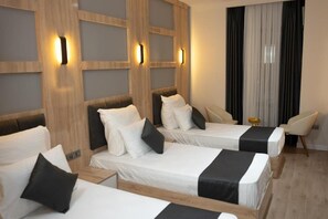 A hotel room with three single beds, a wooden headboard, a small table with a fruit bowl, and a chair. - Golden River Hotel by Continent (Arnavutkoy)