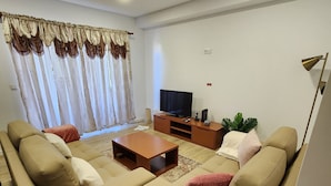 A living room with a sofa set, a coffee table, a TV, and a plant.