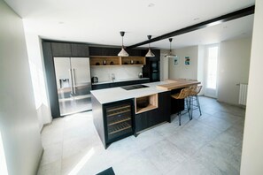 Una cucina moderna con isola integrata, illuminazione a sospensione e zona pranzo con sgabelli da bar.