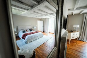 Una camera da letto con un letto, comodini, una cassettiera, uno specchio e una porta.