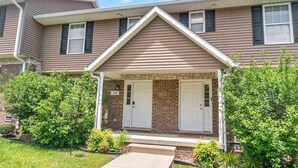 A two-story house with a front porch, two doors, and a brick facade. - Cozy Bloomington Townhouse Close to IU Campus (Bloomington)