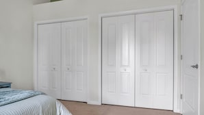 A bedroom with a bed, two white doors, and a small blue nightstand. - Cozy Bloomington Townhouse Close to IU Campus (Bloomington)