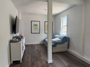 Un dormitorio con cama, cómoda, televisor y fotografías enmarcadas en la pared.