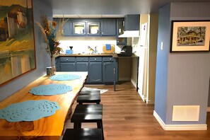 Eine moderne Küche mit blauen Schränken, einem Holztisch mit Platzdeckchen und einer Bank.