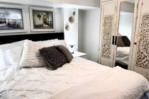 Ein ordentlich bezogenes Bett mit Kissen, einem Nachttisch und einem Schrank mit aufwendigen Verzierungen.