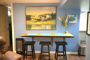 Eine Küche mit Barbereich, Hockern, einem Gemälde und einer Vase mit Blumen.