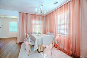 A dining room with a table set for six, peach curtains, and a chandelier. - Cozy Modern Home near Braves Stadium 3BR & 3BA (Smyrna)