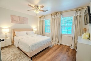 A bedroom with a bed, bedside lamps, a ceiling fan, and a window with curtains. - Cozy Modern Home near Braves Stadium 3BR & 3BA (Smyrna)