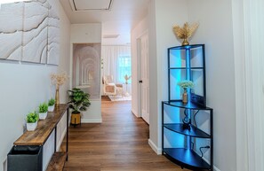 Ein Korridor mit Holzboden, einem schwarzen Metallregal mit blauen LED-Leuchten und einer weißen Tür.