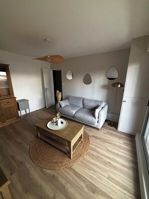 Una sala de estar moderna con una mesa de centro de madera, un sofá gris, un tapete tejido y un ventilador de techo.