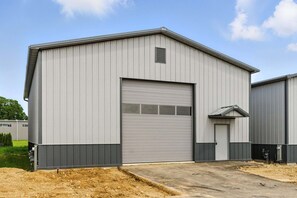 A large industrial building with a grey metal exterior, a large garage door, and a small door on the side. - Awesome barn retreat in welcoming Seattle for a unique stay (Seattle)