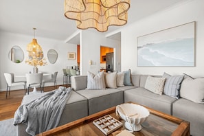 Ein modernes Wohnzimmer mit Ecksofa, einem Essbereich und einer Küche im Hintergrund.