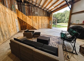 Katettu ulkoalue, jossa on rottingista valmistettuja huonekaluja, grilli ja näkymä ulos.