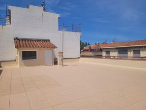 Ein Wohngebiet mit einem weißen Gebäude, einem kleinen Bauwerk mit einem Ziegeldach und blauem Himmel.