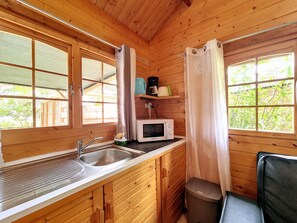 Cocina rústica de cabaña con un lavabo, un microondas y un cubo de basura.