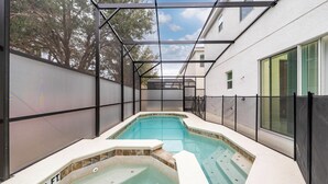 En swimmingpool med ett överbyggt område, omgiven av ett staket, och en byggnad med fönster i bakgrunden.