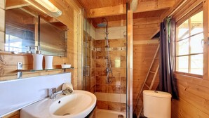 Un bagno in legno con lavandino, specchio, doccia e water.