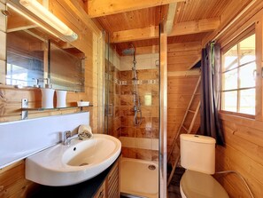 Et badeværelse med træ, et håndvask, et spejl, en bruser og et toilet.