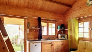 Un accogliente chalet in legno con angolo cottura, piccolo frigorifero, forno a microonde e divano.