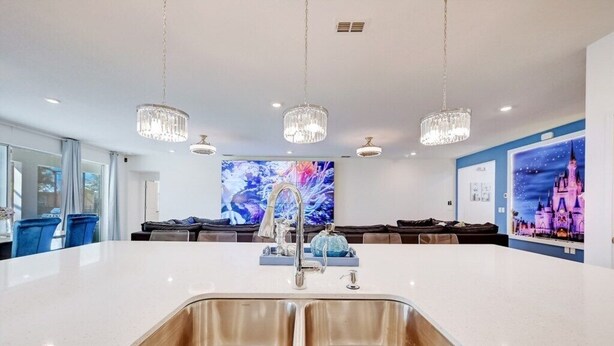 Een moderne keuken met een centraal eiland, roestvrijstalen spoelbakken en hanglampen.